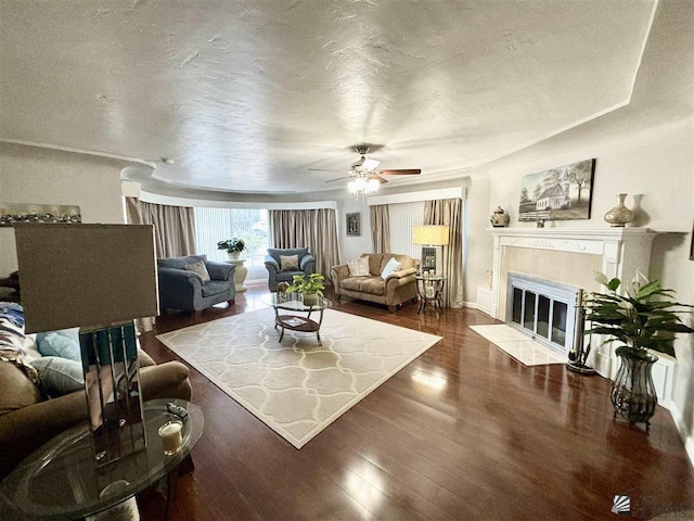 living room featuring ceiling fan, dark wood-type flooring, and a textured ceiling