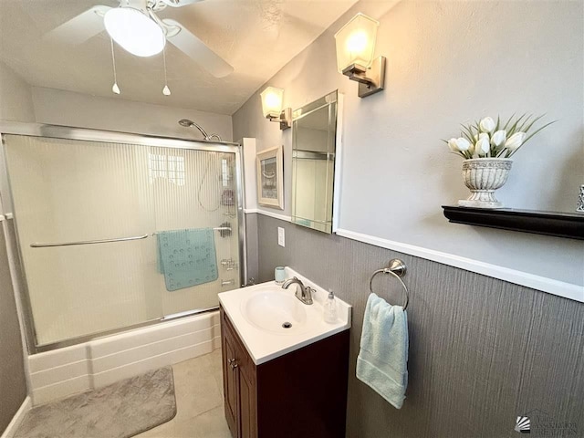 bathroom with tile patterned floors, vanity, ceiling fan, and bath / shower combo with glass door