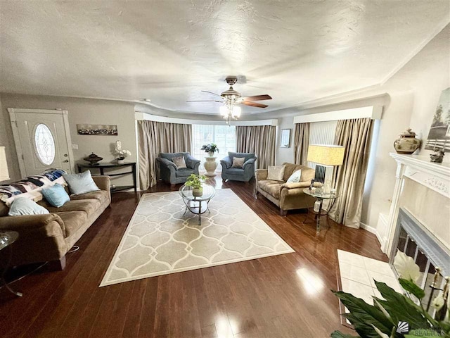 living room with a fireplace, a textured ceiling, dark hardwood / wood-style floors, and ceiling fan