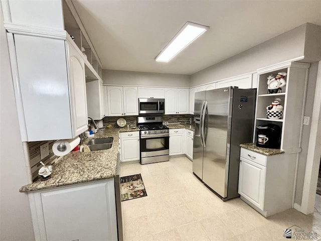 kitchen featuring white cabinetry, sink, stainless steel appliances, tasteful backsplash, and dark stone countertops