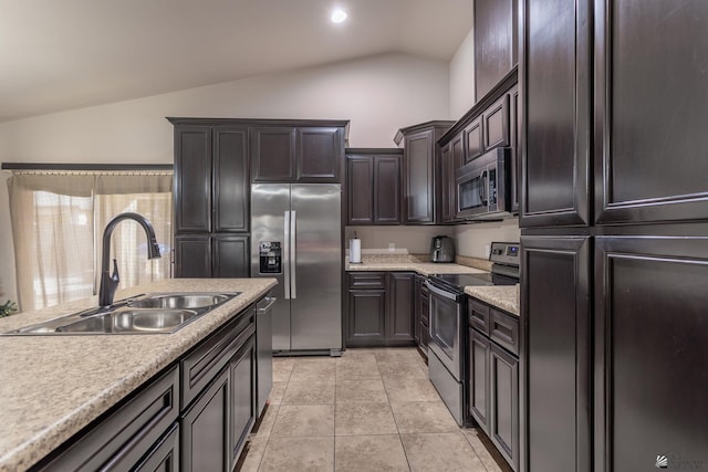 kitchen with dark brown cabinetry, sink, vaulted ceiling, light tile patterned flooring, and appliances with stainless steel finishes