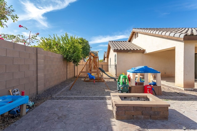 view of patio featuring a playground and an outdoor fire pit