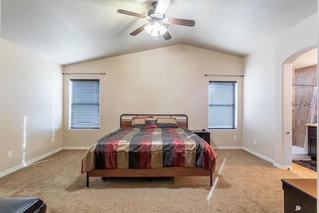 bedroom featuring ensuite bathroom, ceiling fan, light carpet, and vaulted ceiling