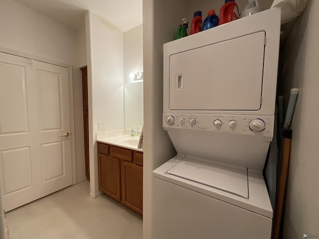 washroom featuring a sink, stacked washer / drying machine, and laundry area