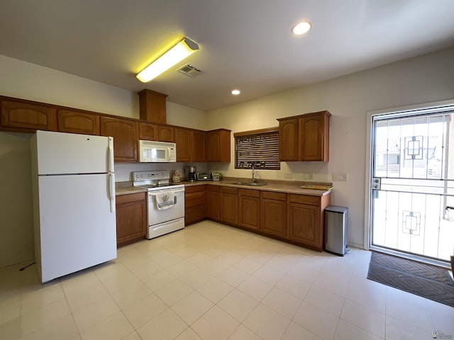 kitchen featuring light countertops, a sink, recessed lighting, and white appliances