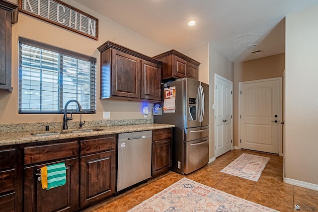 kitchen featuring light stone counters, dark brown cabinets, stainless steel appliances, sink, and light tile patterned floors