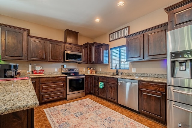 kitchen featuring dark brown cabinetry, sink, light tile patterned floors, and stainless steel appliances