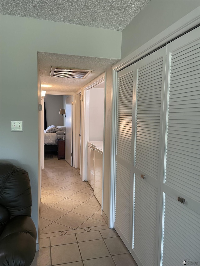 hall with light tile patterned floors and a textured ceiling