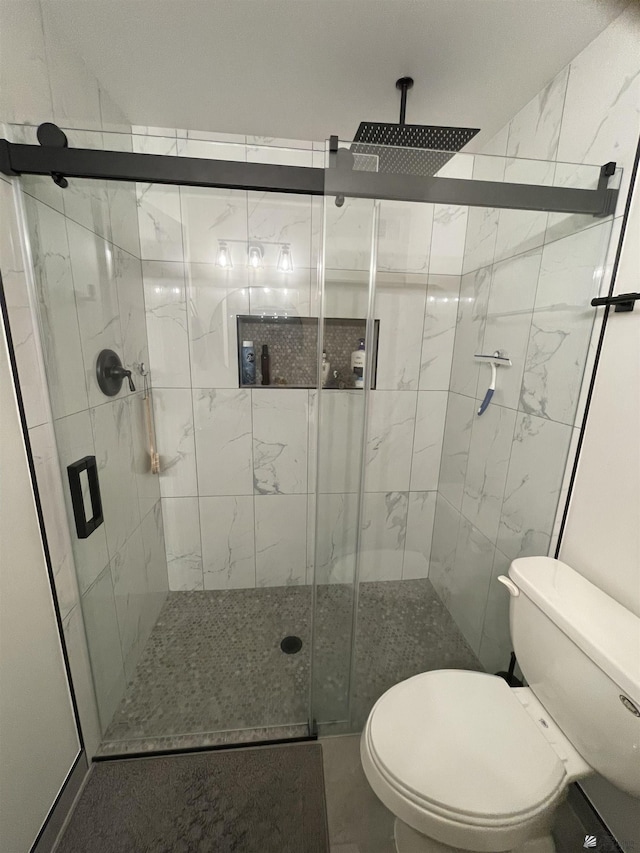 bathroom featuring toilet and a shower with door