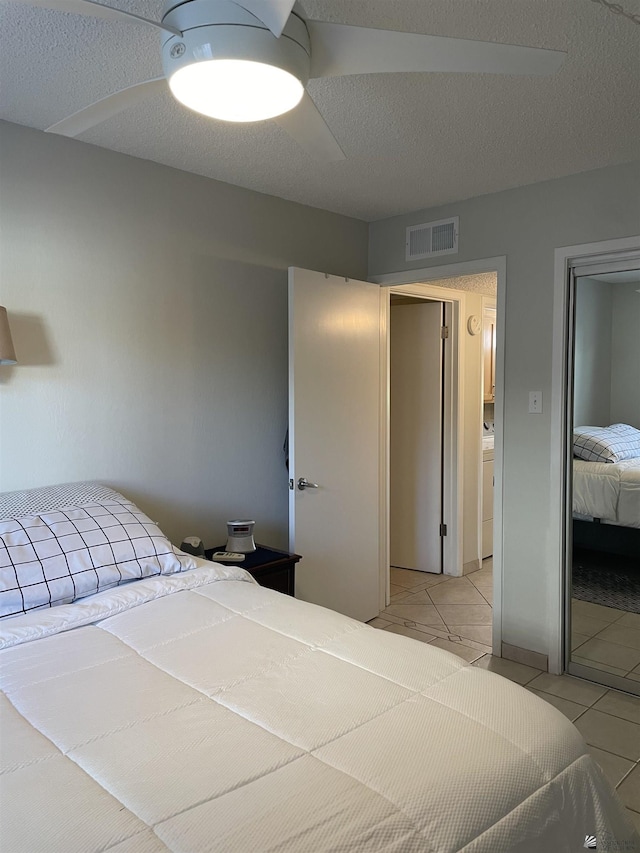 tiled bedroom featuring a textured ceiling and ceiling fan