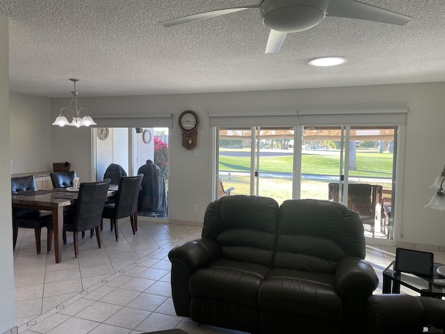 living room with light tile patterned floors, plenty of natural light, a textured ceiling, and ceiling fan with notable chandelier