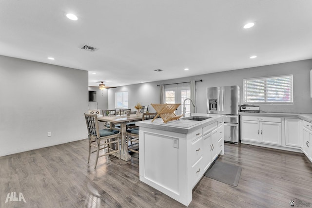 kitchen with sink, white cabinets, hardwood / wood-style flooring, a kitchen island with sink, and stainless steel fridge with ice dispenser