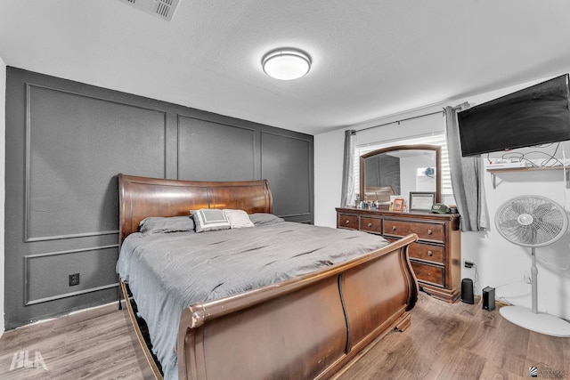 bedroom with a textured ceiling and light hardwood / wood-style floors