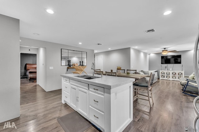 kitchen with sink, ceiling fan, a kitchen island with sink, white cabinetry, and hardwood / wood-style floors