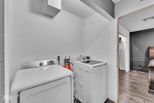 washroom with hardwood / wood-style flooring and washer and dryer