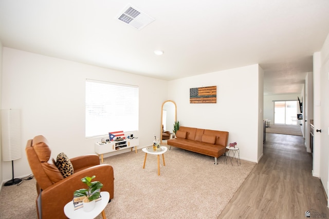 living area featuring visible vents, baseboards, and wood finished floors