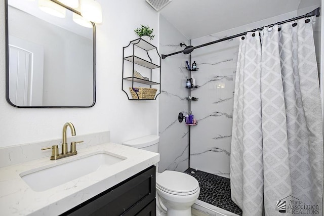 bathroom featuring toilet, a marble finish shower, visible vents, and vanity