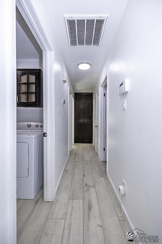 hallway featuring visible vents, light wood-type flooring, washer / dryer, and baseboards