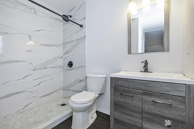 full bathroom with toilet, a marble finish shower, baseboards, and vanity