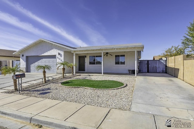 ranch-style home featuring an attached garage, fence, concrete driveway, a gate, and stucco siding