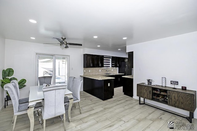 kitchen with tasteful backsplash, light wood-style flooring, freestanding refrigerator, a sink, and recessed lighting