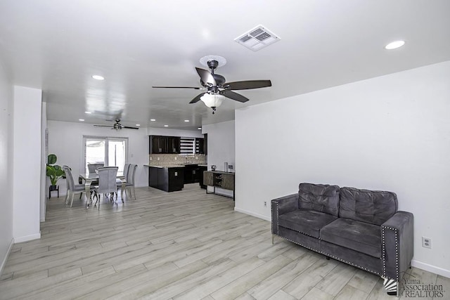 interior space featuring light wood finished floors, a ceiling fan, visible vents, and baseboards