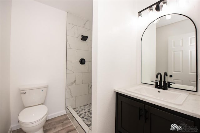 bathroom featuring vanity, hardwood / wood-style flooring, toilet, and tiled shower