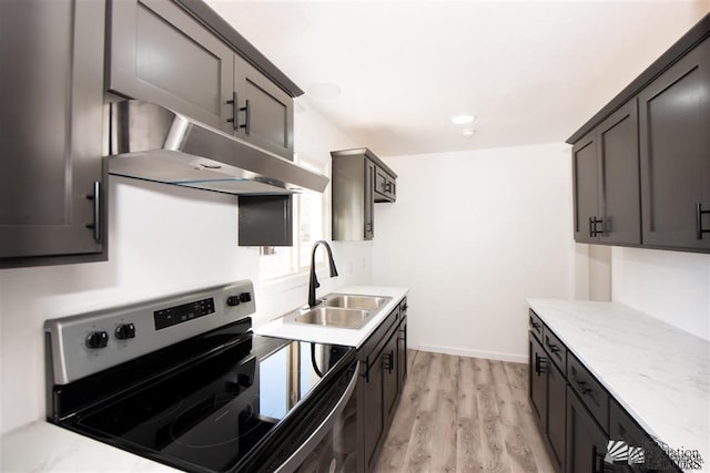 kitchen featuring sink, stainless steel range with electric cooktop, dark brown cabinetry, light stone counters, and light wood-type flooring