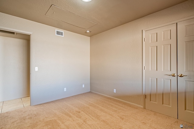 unfurnished bedroom with light colored carpet and a closet