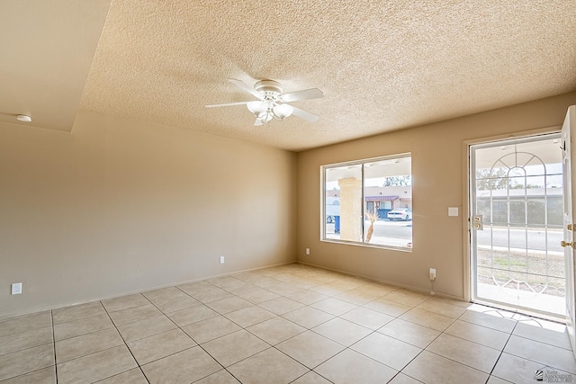 unfurnished room with light tile patterned floors, a textured ceiling, a wealth of natural light, and ceiling fan