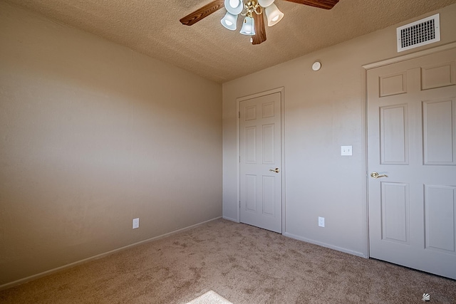 unfurnished bedroom with ceiling fan, light carpet, and a textured ceiling