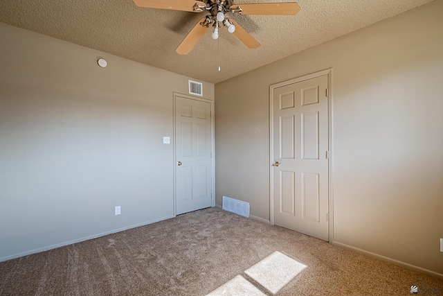 unfurnished bedroom with ceiling fan, light colored carpet, and a textured ceiling