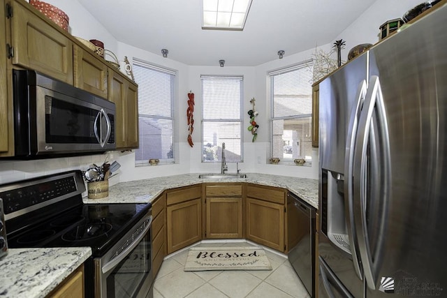 kitchen with light stone countertops, light tile patterned floors, sink, and appliances with stainless steel finishes