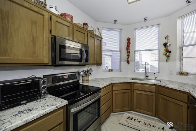 kitchen featuring decorative backsplash, light tile patterned floors, stainless steel appliances, and sink