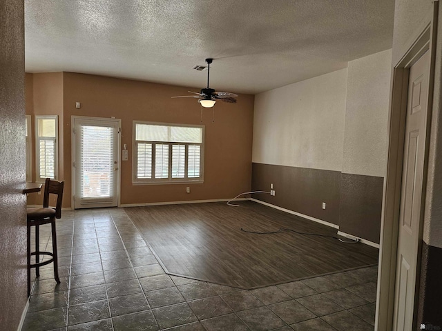 tiled spare room with ceiling fan and a textured ceiling