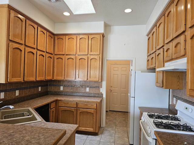 kitchen featuring sink, a skylight, decorative backsplash, light tile patterned flooring, and white range with gas cooktop