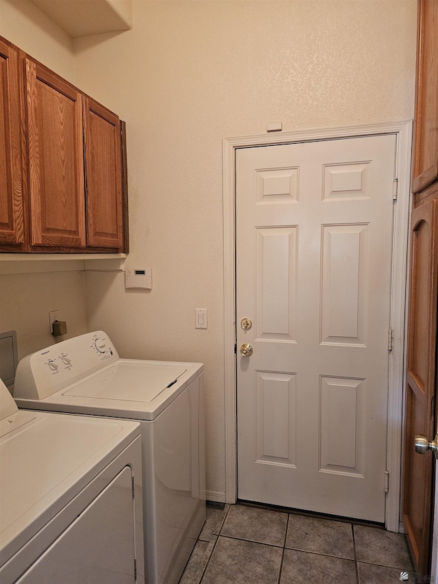 laundry room featuring cabinets, light tile patterned floors, and washing machine and clothes dryer