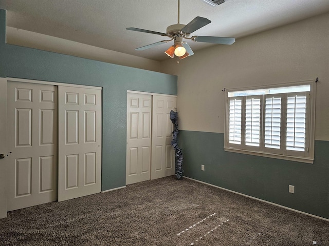 unfurnished bedroom featuring carpet flooring, two closets, and ceiling fan