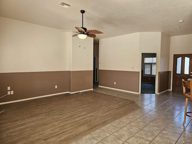 tiled spare room with a textured ceiling and ceiling fan