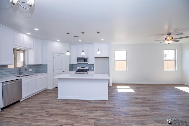 kitchen featuring stainless steel appliances, sink, white cabinetry, and a center island