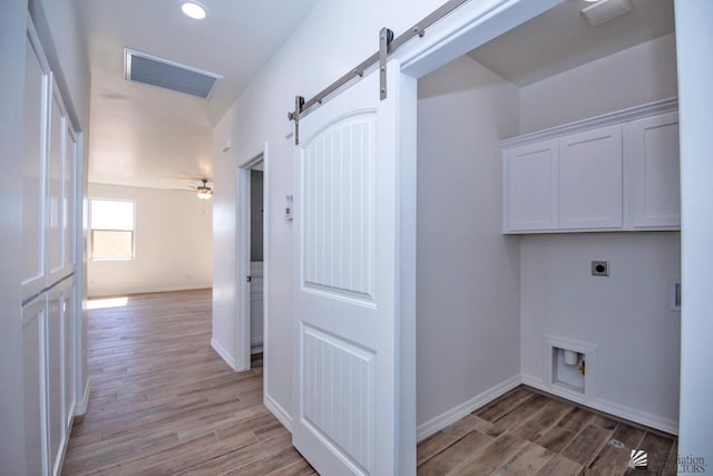 washroom featuring light hardwood / wood-style floors, a barn door, hookup for an electric dryer, washer hookup, and cabinets