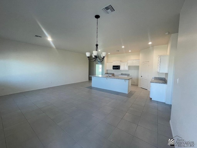 kitchen featuring light tile patterned floors, decorative light fixtures, a center island with sink, an inviting chandelier, and white cabinets