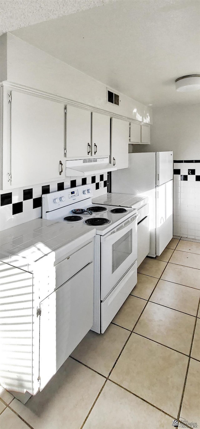 kitchen featuring white cabinets, white electric range, and light tile patterned floors