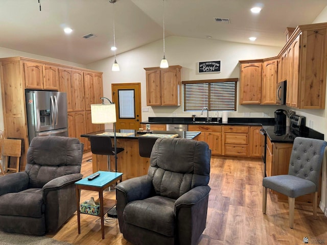 kitchen with lofted ceiling, a kitchen breakfast bar, hanging light fixtures, light hardwood / wood-style flooring, and stainless steel appliances