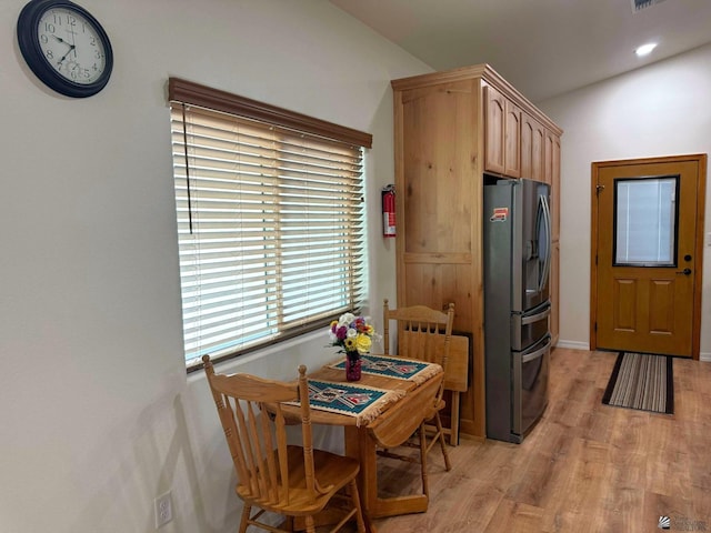 kitchen with stainless steel fridge, light brown cabinets, and light hardwood / wood-style floors