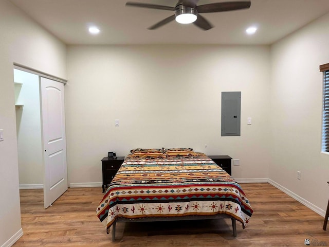 bedroom with ceiling fan, electric panel, and light hardwood / wood-style flooring