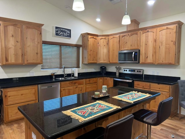 kitchen featuring sink, a center island, stainless steel appliances, light hardwood / wood-style floors, and vaulted ceiling