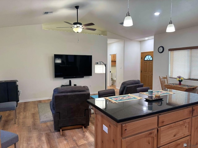 kitchen featuring pendant lighting, a center island, vaulted ceiling, ceiling fan, and light wood-type flooring