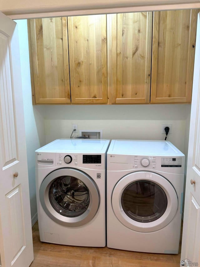 laundry room with cabinets, washer and dryer, and light hardwood / wood-style floors