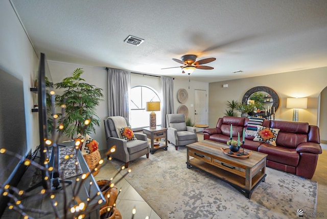 living room featuring tile patterned flooring, a textured ceiling, and ceiling fan